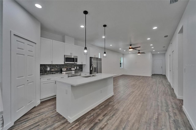 6097 Vermont Ave, New Port Richey, FL 34653 - kitchen featuring stainless steel appliances, recessed lighting, a ceiling fan, white cabinets, and a center island with sink