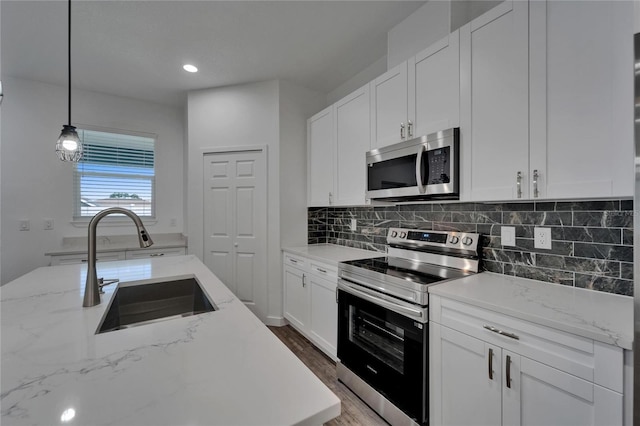 6097 Vermont Ave, New Port Richey, FL 34653 - kitchen with appliances with stainless steel finishes, a sink, tasteful backsplash, white cabinetry, and pendant lighting
