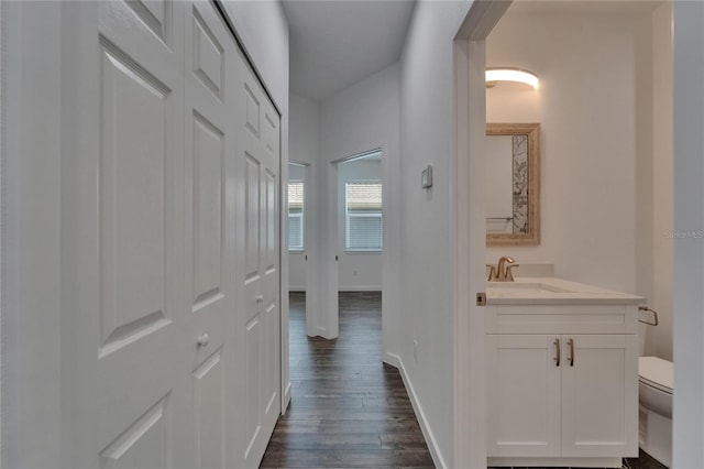 6097 Vermont Ave, New Port Richey, FL 34653 - hallway with a sink, dark wood-style flooring, and baseboards
