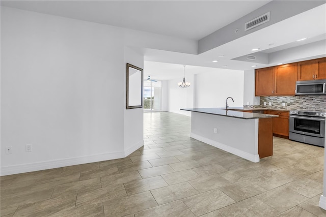 1325 Snell Isle Blvd NE Unit 505, Saint Petersburg, FL 33704 - kitchen featuring appliances with stainless steel finishes, a chandelier, dark countertops, decorative backsplash, and brown cabinetry