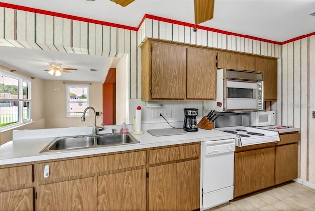 1666 Souvenir Dr, Clearwater, FL 33755 - kitchen with white appliances, a sink, light countertops, and brown cabinetry