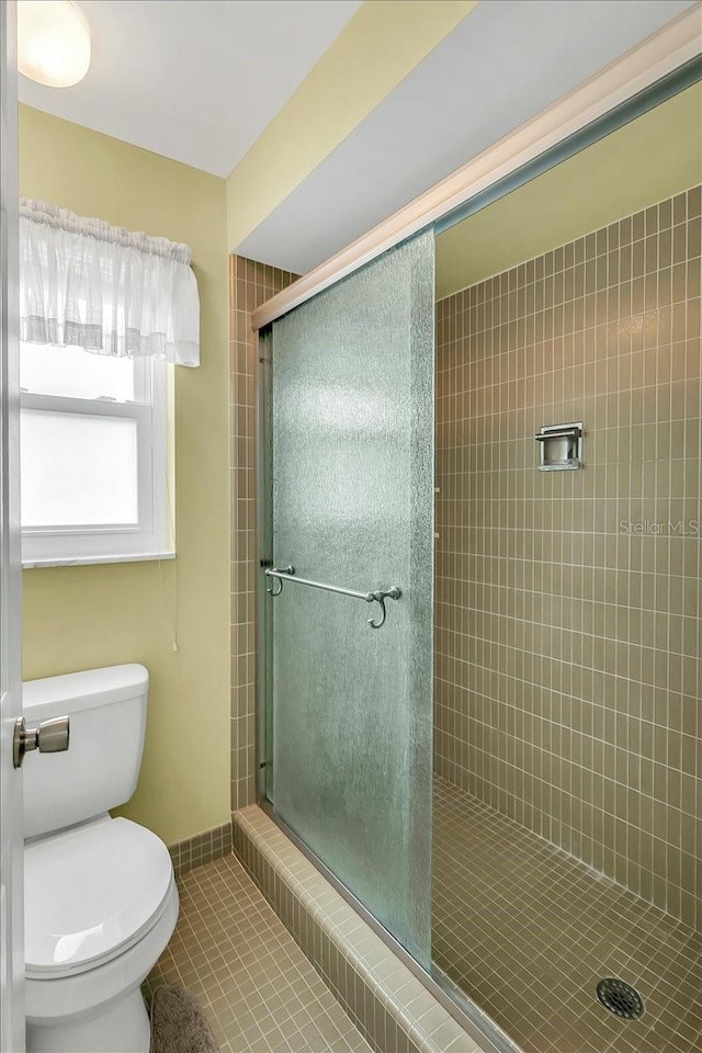 1666 Souvenir Dr, Clearwater, FL 33755 - bathroom with tile patterned floors, a stall shower, toilet, and baseboards
