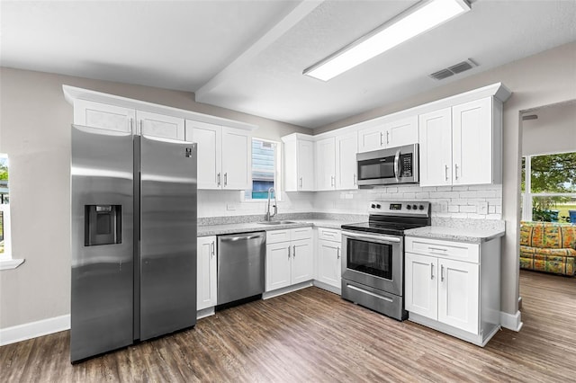 kitchen featuring appliances with stainless steel finishes, a sink, dark wood-style floors, tasteful backsplash, and white cabinets