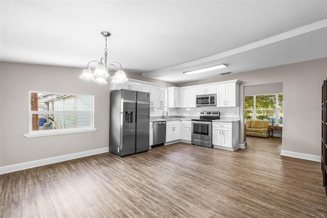 kitchen featuring stainless steel appliances, a sink, dark wood-type flooring, light countertops, and baseboards