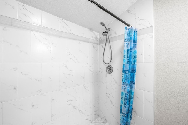 full bath with a textured ceiling and tiled shower