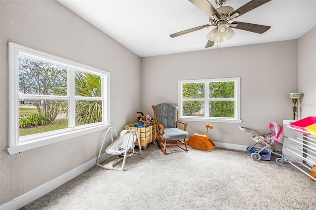 sitting room featuring carpet, baseboards, and a ceiling fan