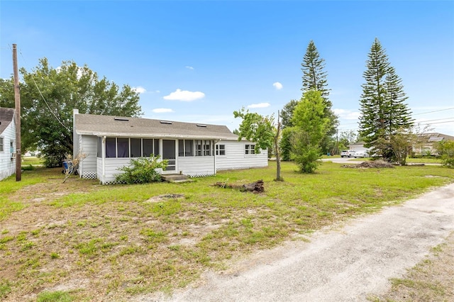 view of front of property featuring a sunroom, a front lawn, and entry steps