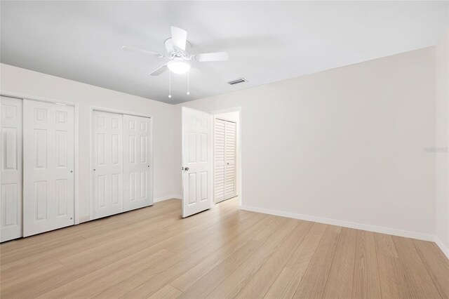 6025 Shore Blvd S Unit 409, Gulfport, FL 33707 - unfurnished bedroom with multiple closets, light wood-style floors, baseboards, and a ceiling fan