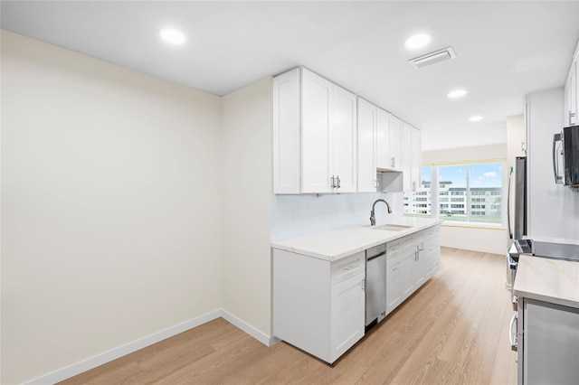 6025 Shore Blvd S Unit 409, Gulfport, FL 33707 - kitchen featuring a sink, stainless steel dishwasher, light wood finished floors, white cabinetry, and baseboards
