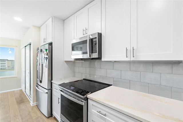 6025 Shore Blvd S Unit 409, Gulfport, FL 33707 - kitchen with appliances with stainless steel finishes, white cabinets, backsplash, light wood-type flooring, and recessed lighting