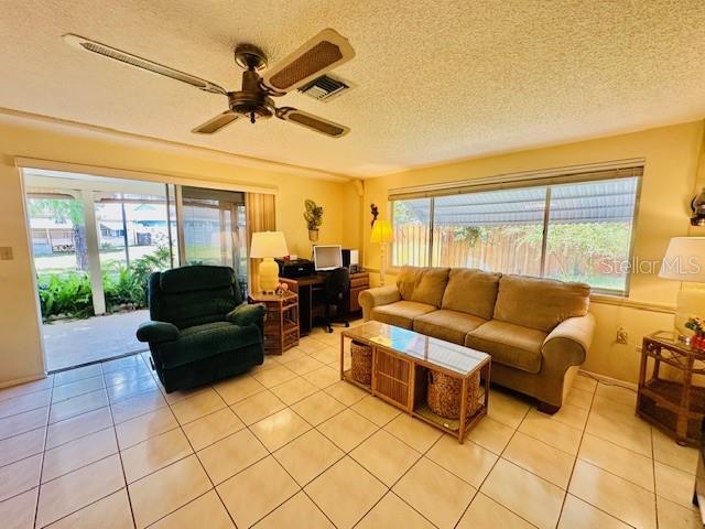 living room featuring light tile patterned floors, a ceiling fan, and a textured ceiling