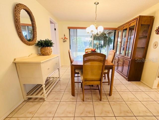 dining room featuring a chandelier, light tile patterned floors, and baseboards
