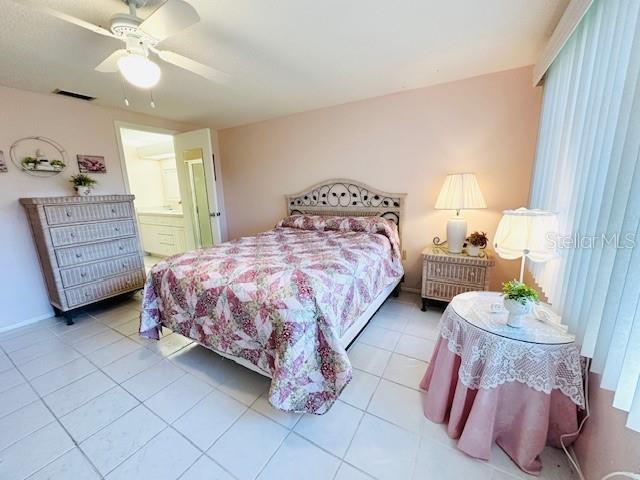 tiled bedroom with a ceiling fan and ensuite bathroom
