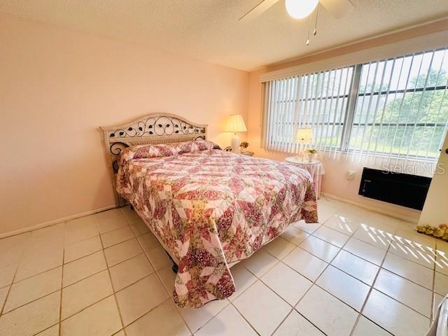 bedroom with multiple windows, tile patterned flooring, a textured ceiling, and baseboards
