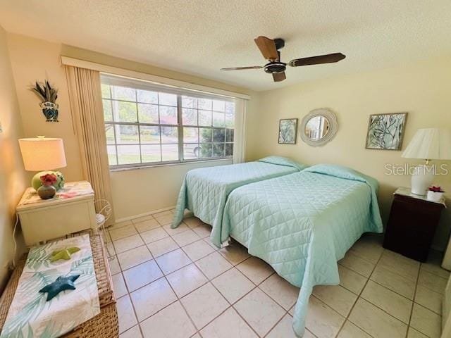 bedroom featuring a textured ceiling, light tile patterned flooring, ceiling fan, and baseboards