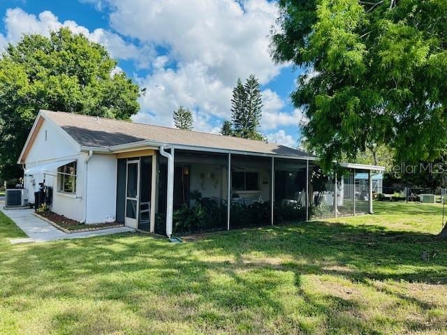 back of property with central AC, a yard, and a sunroom
