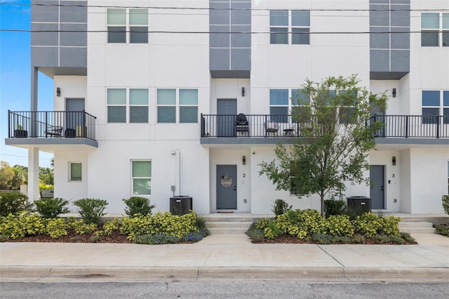 view of front of home with stucco siding, central AC unit, and a balcony