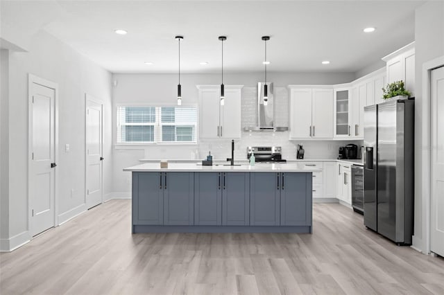 kitchen with appliances with stainless steel finishes, wall chimney exhaust hood, beverage cooler, light wood-style floors, and light countertops