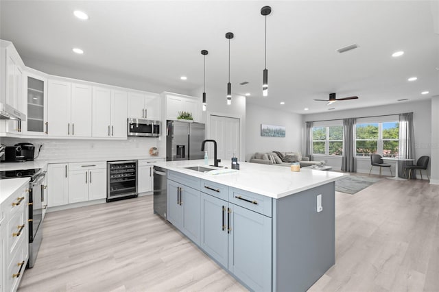 kitchen with wine cooler, appliances with stainless steel finishes, open floor plan, white cabinetry, and recessed lighting
