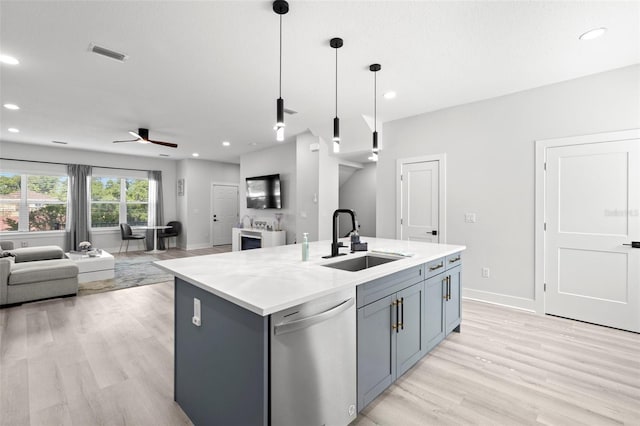 kitchen with stainless steel dishwasher, a sink, open floor plan, light wood-style floors, and a kitchen island with sink