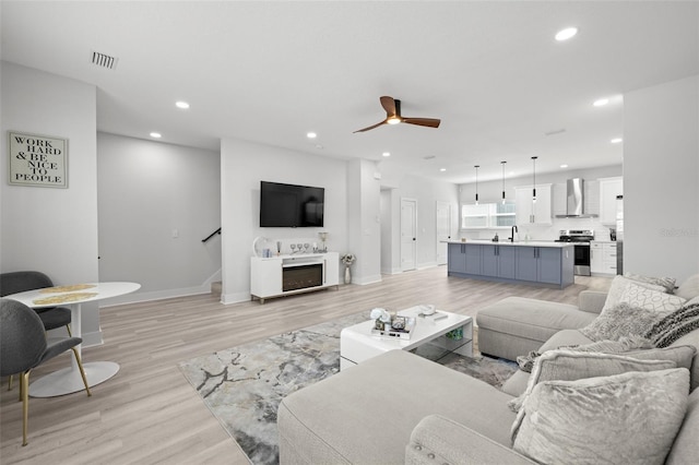 living area with light wood-type flooring, ceiling fan, recessed lighting, and baseboards