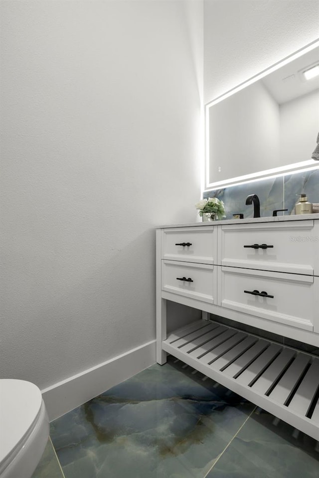 bathroom with baseboards, toilet, and vanity