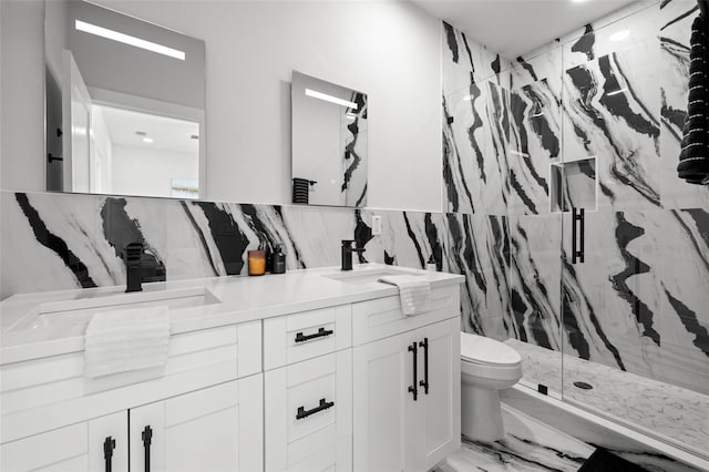 bathroom featuring marble tiled flooring, a marble finish shower, toilet, double vanity, and tile walls
