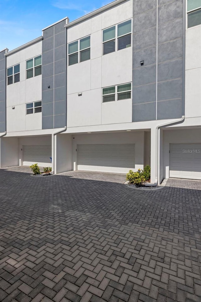 view of front facade with an attached garage, driveway, and stucco siding