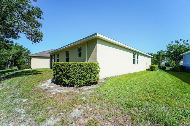 view of side of property with stucco siding and a lawn
