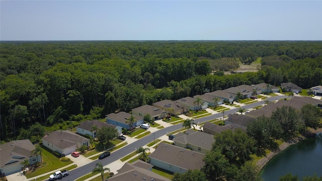 aerial perspective of suburban area featuring a forest and a large body of water