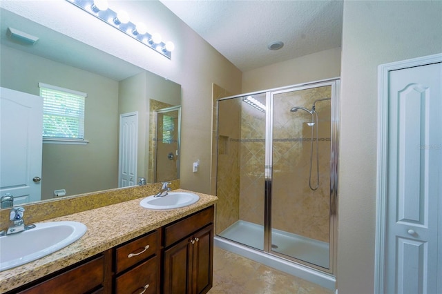 bathroom with a stall shower, double vanity, and a textured ceiling