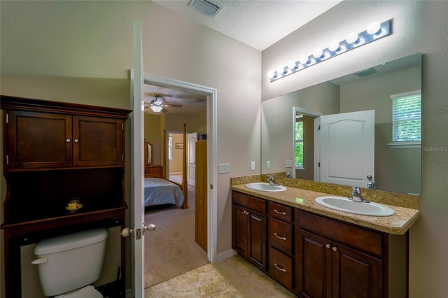 bathroom featuring toilet, plenty of natural light, double vanity, and ensuite bathroom