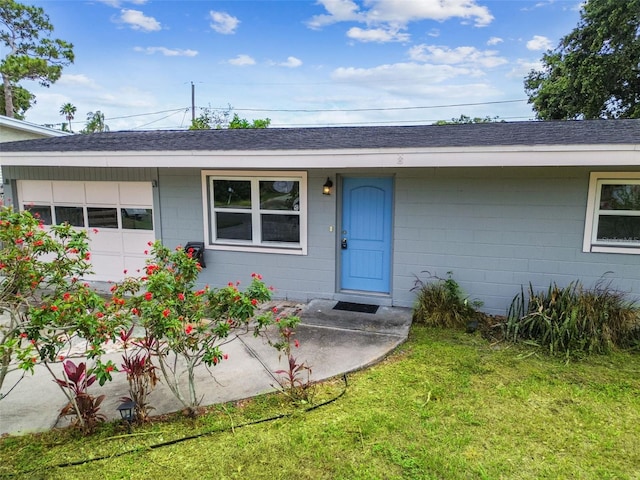 8528 Iris Ave, Seminole, FL 33777 - view of exterior entry with concrete block siding, roof with shingles, and a lawn