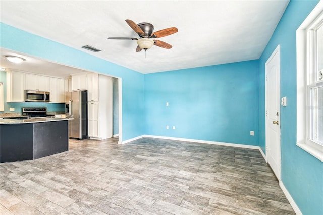 8528 Iris Ave, Seminole, FL 33777 - kitchen with appliances with stainless steel finishes, ceiling fan, baseboards, and white cabinets
