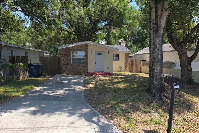 4607 N 35th St, Tampa, FL 33610 - view of front facade featuring brick siding, fence, concrete driveway, and a chimney