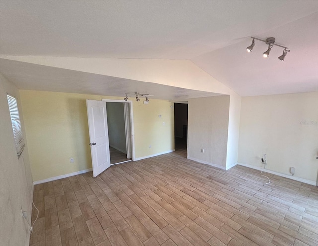 4607 N 35th St, Tampa, FL 33610 - unfurnished room featuring rail lighting, lofted ceiling, light wood-style flooring, and baseboards