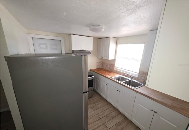 4607 N 35th St, Tampa, FL 33610 - kitchen featuring appliances with stainless steel finishes, a sink, under cabinet range hood, white cabinets, and a textured ceiling