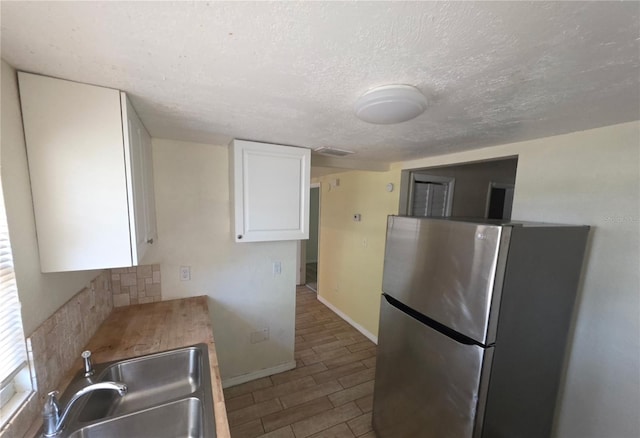 4607 N 35th St, Tampa, FL 33610 - kitchen with freestanding refrigerator, a sink, white cabinets, backsplash, and a textured ceiling