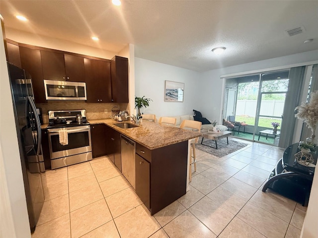 13140 Summerton Dr, Orlando, FL 32824 - kitchen with appliances with stainless steel finishes, a peninsula, a sink, open floor plan, and a kitchen bar