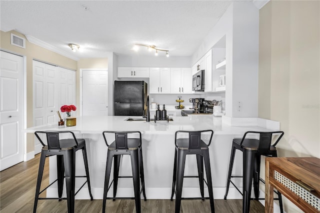 kitchen with stainless steel microwave, freestanding refrigerator, a peninsula, electric range oven, and a breakfast bar