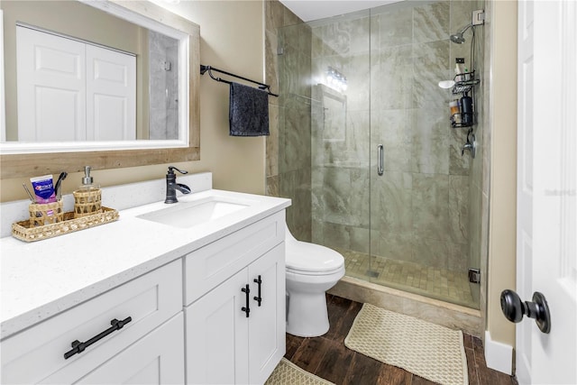 full bath featuring a shower stall, vanity, toilet, and wood finished floors