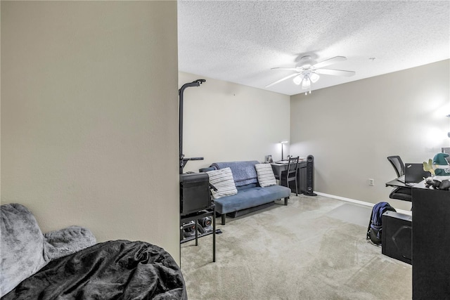carpeted office space with ceiling fan, a textured ceiling, and baseboards