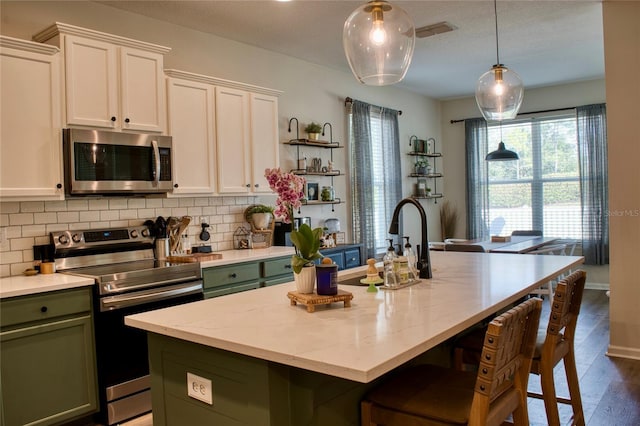 12327 Eagle Swoop Pl, Riverview, FL 33579 - kitchen featuring stainless steel appliances, green cabinets, backsplash, a sink, and white cabinetry