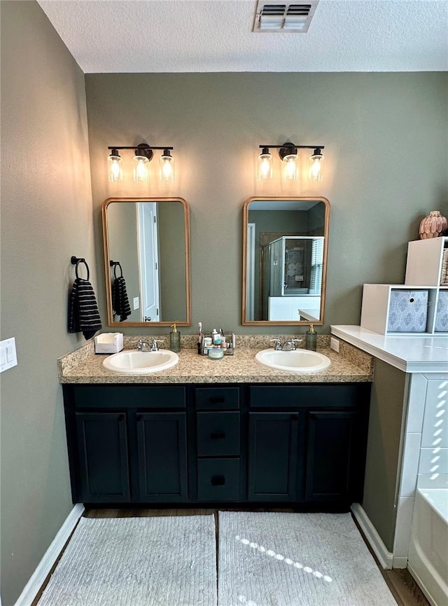 12327 Eagle Swoop Pl, Riverview, FL 33579 - bathroom with double vanity, a textured ceiling, a shower stall, a tub to relax in, and baseboards