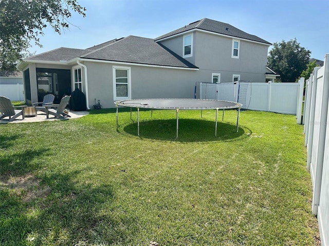 12327 Eagle Swoop Pl, Riverview, FL 33579 - rear view of house with an outdoor fire pit, a trampoline, stucco siding, roof with shingles, and a patio area