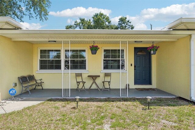 1450 Seabreeze St, Clearwater, FL 33756 - entrance to property with covered porch, stucco siding, and a lawn