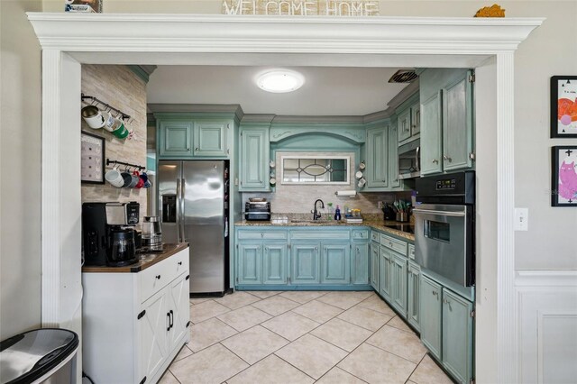 1450 Seabreeze St, Clearwater, FL 33756 - kitchen featuring appliances with stainless steel finishes, decorative backsplash, green cabinetry, a sink, and light tile patterned flooring