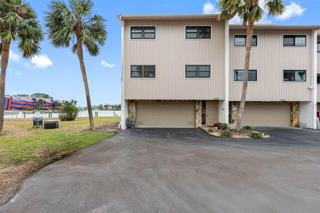 12360 Capri Cir N Unit 106, Treasure Island, FL 33706 - view of front of property featuring stone siding, an attached garage, asphalt driveway, and a water view