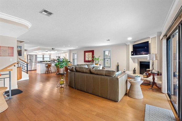 12360 Capri Cir N Unit 106, Treasure Island, FL 33706 - living room with stairs, a fireplace with raised hearth, light wood-type flooring, crown molding, and recessed lighting