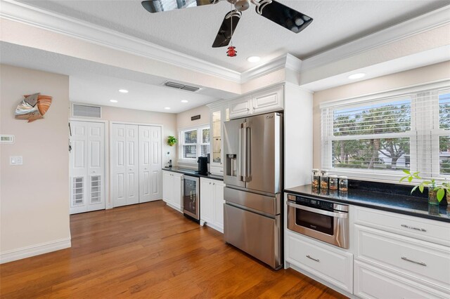 12360 Capri Cir N Unit 106, Treasure Island, FL 33706 - kitchen featuring appliances with stainless steel finishes, dark countertops, wine cooler, a ceiling fan, and ornamental molding
